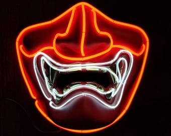 May include: A red neon sign in the shape of a Japanese Oni mask with a white neon outline. The mask has a wide open mouth with sharp teeth.