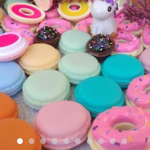 May include: A collection of miniature round macaron-shaped containers and donut-shaped items in various pastel and bright colors including pink, blue, orange, mint green, and yellow, featuring a small white unicorn figurine and dark chocolate-colored pieces.