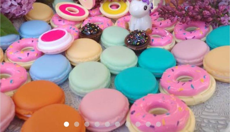May include: A collection of miniature round macaron-shaped containers and donut-shaped items in various pastel and bright colors including pink, blue, orange, mint green, and yellow, featuring a small white unicorn figurine and dark chocolate-colored pieces.