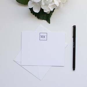 Könnte beinhalten: Eine weiße Karte mit einem marineblauen Monogramm der Buchstaben "M|C" in einem Quadrat.