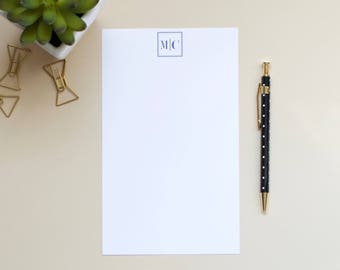 May include: A white sheet of paper with a blue square in the top center that says "M|C". A black pen with white polka dots is on the right side of the paper.