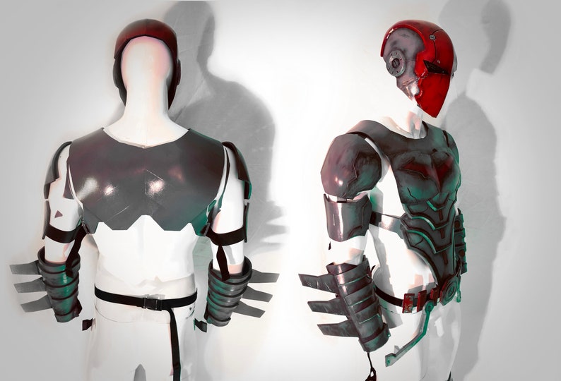 May include: A black and grey costume armour with a red helmet. The armour has a textured surface and is made of a hard material. The helmet has a visor and a red paint job.