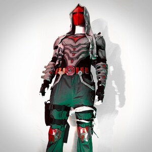 May include: A red and grey superhero costume with a red mask and a grey hooded cape. The costume has a belt with a red buckle and a red symbol on the chest. The costume is worn by a mannequin.