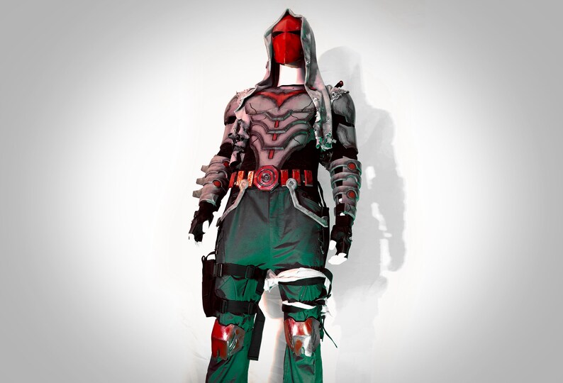 May include: A red and grey superhero costume with a red mask and a grey hooded cape. The costume has a belt with a red buckle and a red symbol on the chest. The costume is worn by a mannequin.