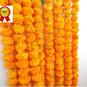 May include: A garland of yellow marigold flowers, strung together with green thread. The garland is made of paper and is a popular decoration for Indian festivals and celebrations.