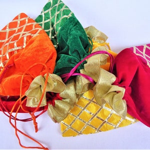 May include: Five colorful drawstring pouches with gold trim. The pouches are made of velvet and have a diamond pattern. The pouches are in the colors orange, green, yellow, red, and pink.