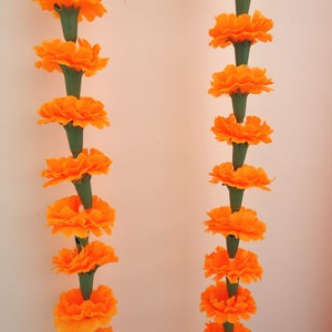 Puede incluir: Dos guirnaldas verticales de cal&eacute;ndulas de color naranja brillante, cada una con m&uacute;ltiples flores y tallos verdes, sobre un fondo claro. Las flores completamente florecidas crean una exhibici&oacute;n vibrante y festiva. Decoraci&oacute;n tradicional.