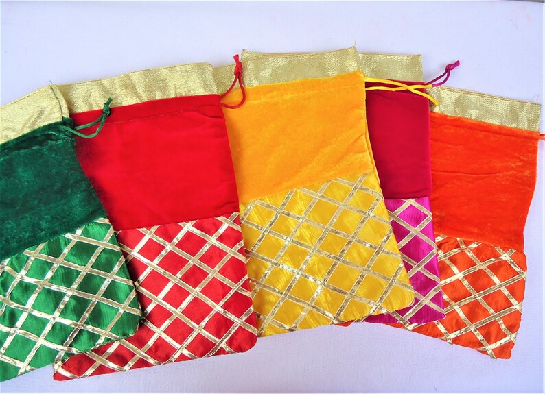 May include: Five colorful drawstring bags with gold trim and a diamond pattern. The bags are made of velvet and have a contrasting fabric bottom. The colors are green, red, yellow, burgundy, and orange.