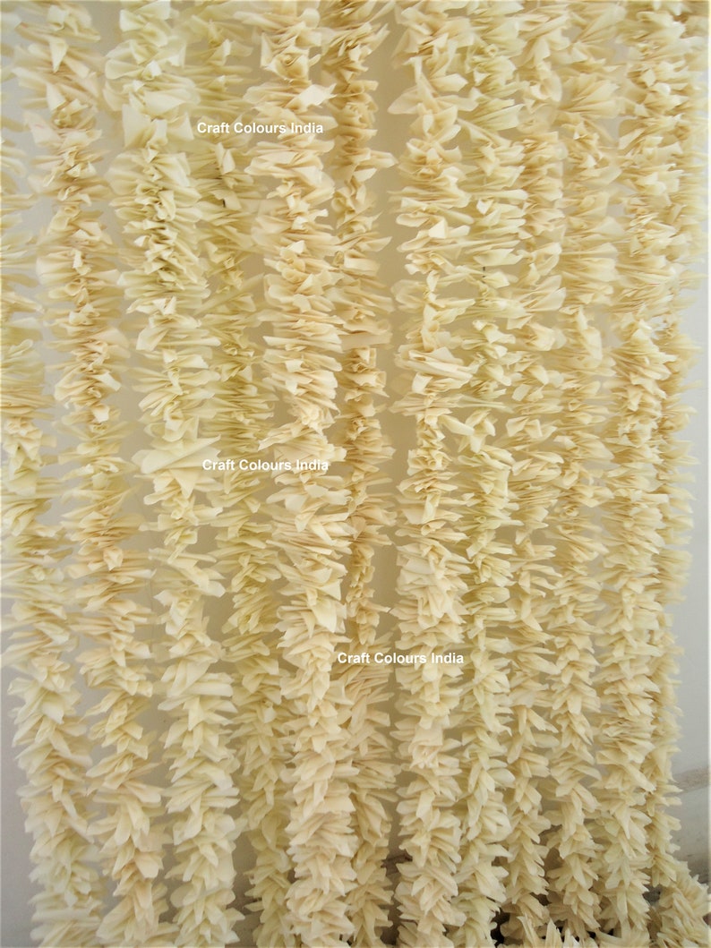 May include: A close-up of a cream-colored garland made of tissue paper. The garland is hanging in a doorway or window. The text "Craft Colours India" is visible on the garland.