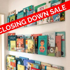 May include: A wall-mounted bookshelf displays a collection of colorful children's books. The books are arranged on clear acrylic shelves. The text "CLOSING DOWN SALE" is displayed across the image in a red banner.