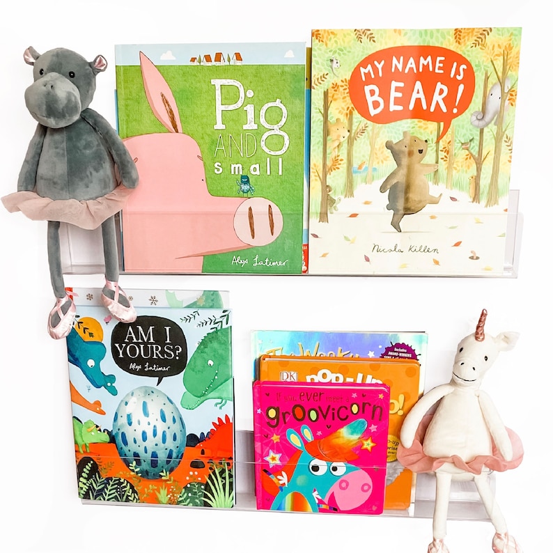 May include: A set of children's books on a white shelf. The books are about a pig, a bear, a dinosaur, and a unicorn. The books are all colorful and have illustrations.