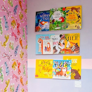 May include: A shelf with a collection of children's books about tigers. The books have colorful covers with illustrations of tigers and other animals. The titles of the books include "The Worry Tiger", "Tiger in the Garden", "How to Talk to a Tiger", "Today I'm the Tiger Who Came to Tea", "Mum's a Tiger", "Justus and His Mile", "Mr. Tiger", "Go Get 'Em Tiger!" and "The Lion's Ride".