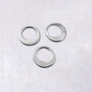 May include: Three silver metal rings, each with a slightly different shape and size. The rings are smooth and shiny.