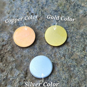 May include: Three circular flat discs arranged in a triangular formation. One disc is copper-coloured, one is gold-coloured, and one is silver-coloured. Each disc is labelled with text pointing to it: Copper Color, Gold Color, and Silver Color.