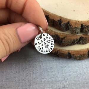 May include: Silver dog tag with the name "LUNA" and a small tree design surrounded by stars and numbers.