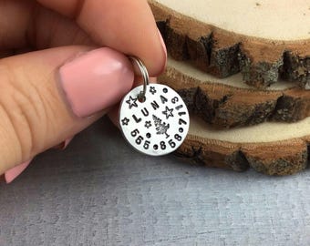 May include: Silver dog tag with the name "LUNA" and a small tree design surrounded by stars and numbers.
