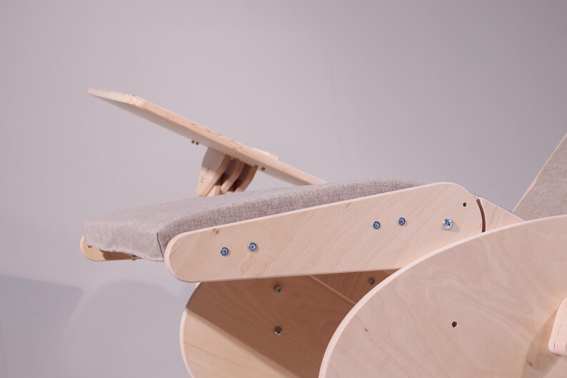 May include: A wooden chair with a light gray upholstered seat and an adjustable backrest. The chair is constructed from light-colored wood and features visible screws. The design is minimalist and modern.