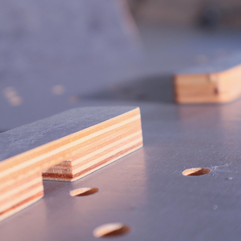 K&ouml;nnte beinhalten: Nahaufnahme von geschichteten Holzst&uuml;cken in hellbraunen und beigen Farbt&ouml;nen. Das rechteckige Holz ist Teil eines Bauprojekts. Der Hintergrund ist eine hellgraue Oberfl&auml;che mit kleinen, ovalen L&ouml;chern. Ma&szlig;e in Zentimetern.