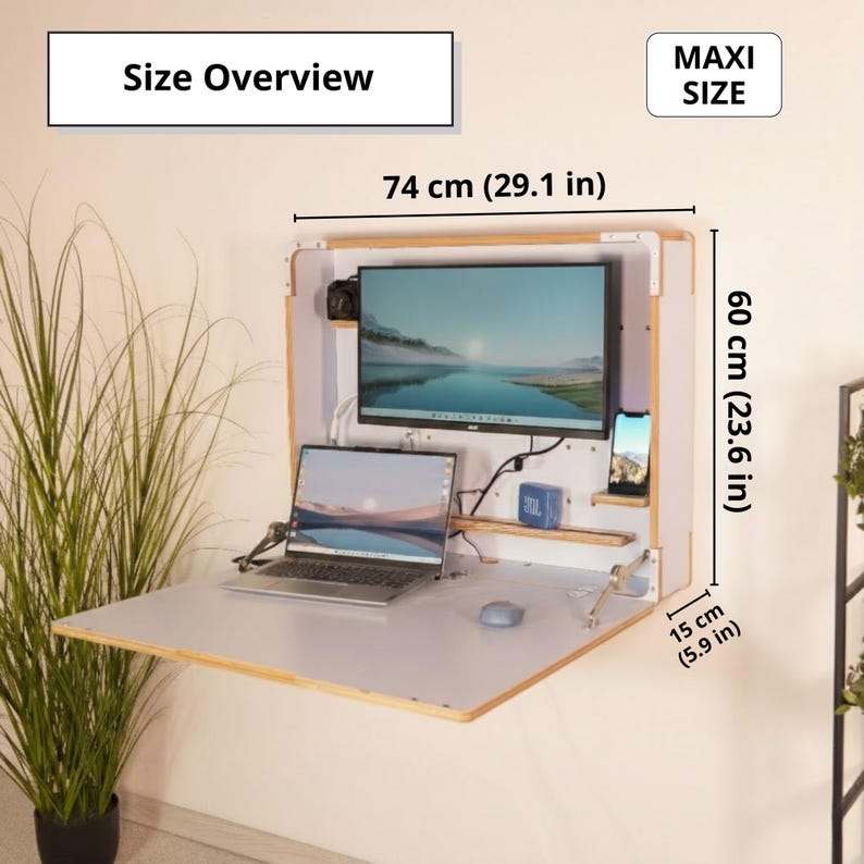 May include: A wall-mounted fold-down desk with a light wood frame and white surface. Text reads Size Overview and MAXI SIZE. Dimensions are 29.1 inches wide, 23.6 inches high, and 5.9 inches deep. It holds a monitor, laptop, and phone.