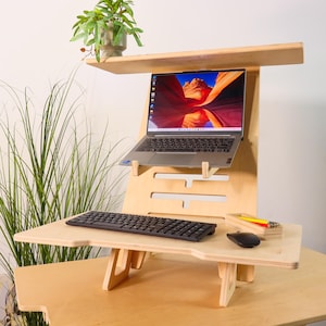 May include: A wooden standing desk with a laptop, keyboard, and mouse. The desk is made of light wood and has a shelf for the laptop. The keyboard and mouse are on the lower shelf.