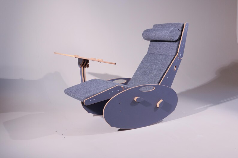 K&ouml;nnte beinhalten: Ein moderner, ergonomischer Schaukelstuhl in einem ged&auml;mpften Blau-Grau. Der Stuhl verf&uuml;gt &uuml;ber eine Kopfst&uuml;tze, eine Armlehne und einen kleinen Holztisch. Sitz und R&uuml;ckenlehne sind mit passendem Stoff bezogen. Die Basis ist zum Schaukeln konzipiert.