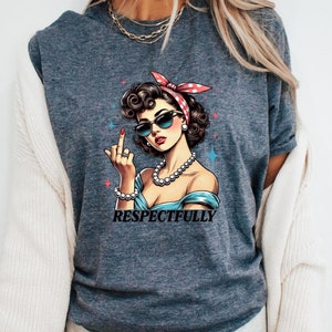 May include: A dark gray t-shirt with a graphic of a woman wearing sunglasses and a red and white bandana. The text "RESPECTFULLY" is printed below the graphic.