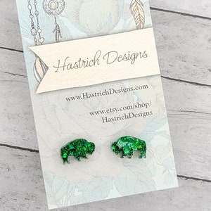 May include: A pair of green glitter buffalo earrings on a white card with the text "Hastrich Designs" and website information.