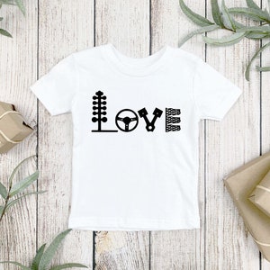 May include: White baby onesie with black racing-themed graphics spelling out the word "LOVE".