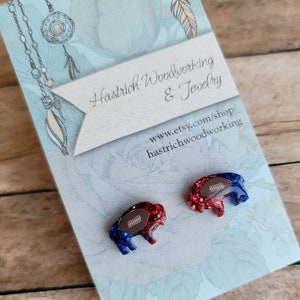 May include: A pair of blue and red glitter buffalo earrings with a football design. The earrings are on a white card with the text "Hastrich Woodworking & Jewelry" and "www.etsy.com/shop/hastrichwoodworking".