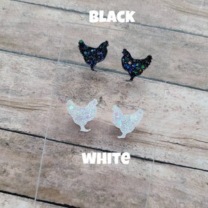 May include: Two pairs of glitter chicken earrings, one pair is black and one pair is white.