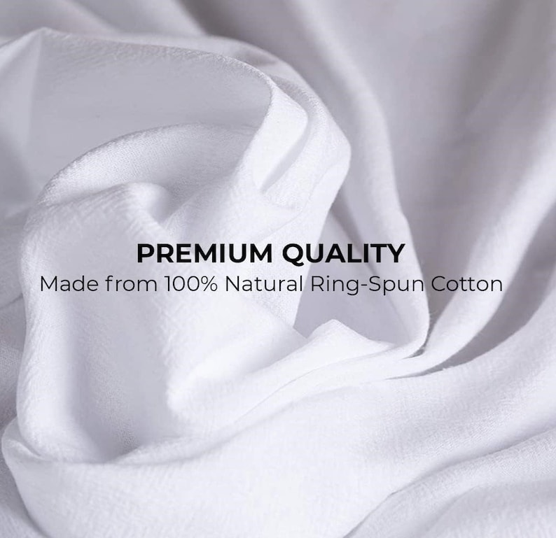 May include: Close-up of white fabric with a textured surface. The fabric is made from 100% natural ring-spun cotton. The text "PREMIUM QUALITY" is printed on the fabric.
