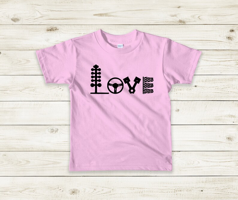 May include: Pink t-shirt with a black graphic of racing-themed icons spelling out the word "LOVE".