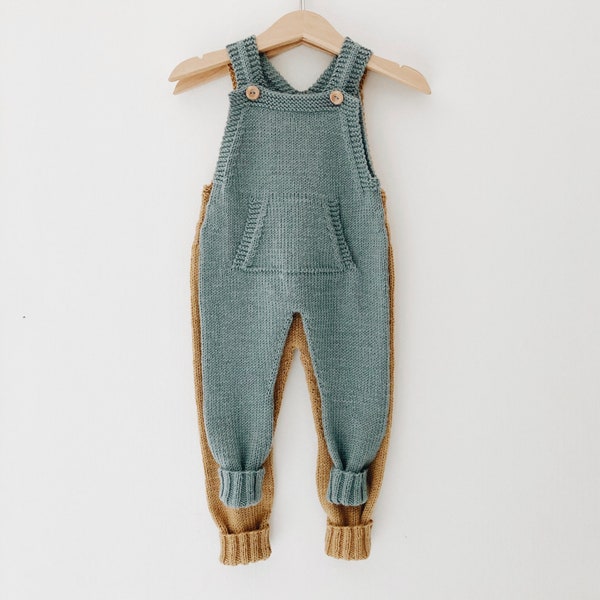 May include: A knitted baby overall with a blue top and brown legs. The overall has a pocket on the front and straps that button at the shoulders.