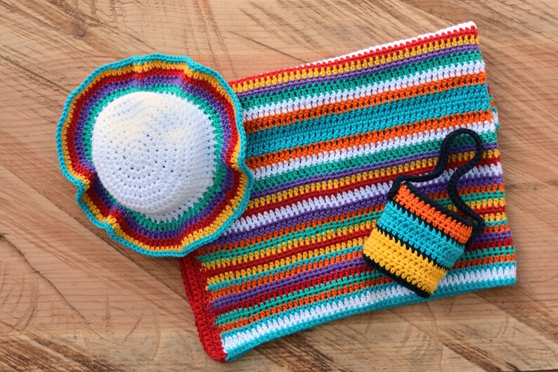 May include: A set of crocheted items in rainbow colors, including a hat, a blanket, and a small bag. The items are made with a variety of colorful yarns and have a striped pattern.