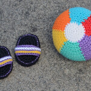 May include: Two crocheted black sandals with purple, white, and yellow stripes and a multi-colored crocheted beach ball.