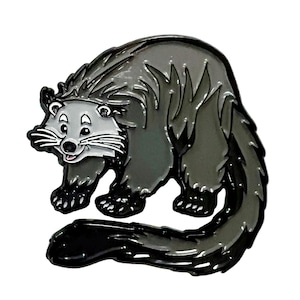 Puede incluir: Un pin que representa un binturong de dibujos animados, en tonos grises y negros. El binturong tiene una cara blanca, bigotes y una expresión sonriente. El pin probablemente está hecho de metal con un acabado de esmalte.