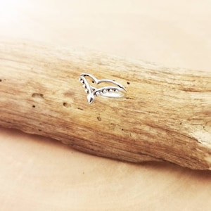 Op de afbeelding: Een zilveren ring met een V-vormig ontwerp en kleine kralen langs de randen.