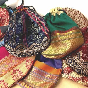 Könnte beinhalten: Eine Sammlung von Kordelzugbeuteln in verschiedenen Farben und Mustern. Die Beutel weisen verzierte Designs mit goldenen, roten, blauen und grünen Stoffen auf. Jeder Beutel hat einen Kordelzugverschluss.