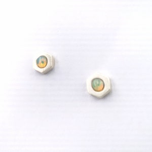 Peut inclure: Une paire de boucles d'oreilles en argent avec une forme hexagonale et une petite pierre d'opale irisée au centre de chacune.