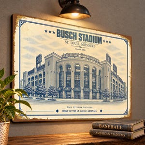 May include: A rectangular metal sign featuring a vintage-style blue and cream illustration of Busch Stadium in St. Louis, Missouri. The text reads Busch Stadium, St. Louis, Missouri, Opened 2006, Main Exterior Elevation, Home of the St. Louis Cardinals.