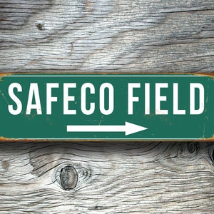 May include: A green metal sign with white text that reads "SAFECO FIELD" and a white arrow pointing to the right.