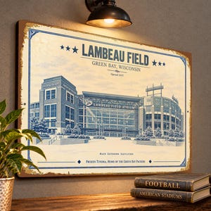Könnte beinhalten: Ein rechteckiges Metallschild mit einer blau-cremefarbenen Illustration des Lambeau Field in Green Bay, Wisconsin. Der Text lautet Lambeau Field, Green Bay, Wisconsin, Opened 1957, Main Exterior Elevation und Frozen Tundra, Home of the Green Bay Packers.