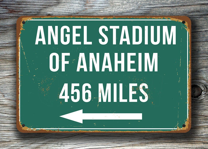 May include: A green metal sign with white text that reads "Angel Stadium of Anaheim 456 Miles" with a white arrow pointing to the left.
