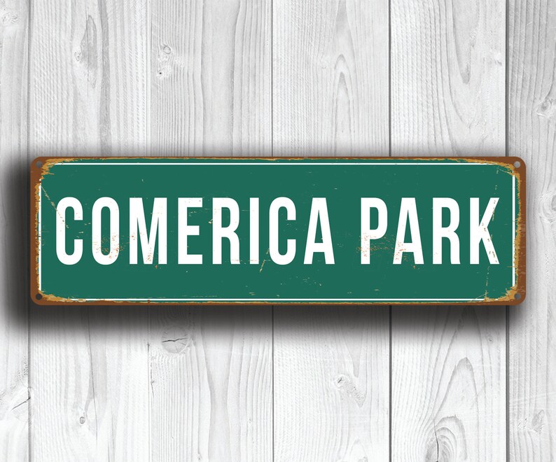 May include: A vintage-style metal sign with a green background and white lettering that reads "Comerica Park". The sign has a distressed, rusty look.