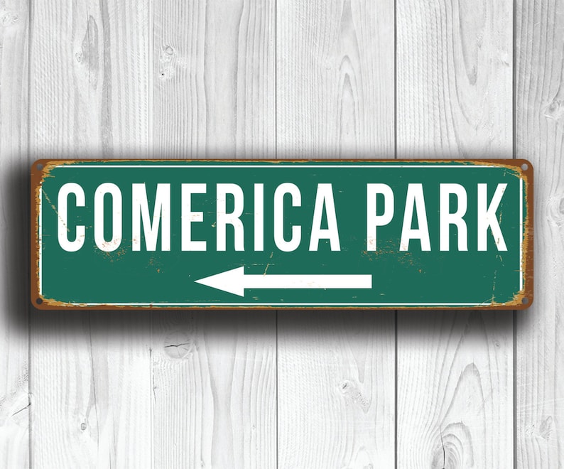 May include: A green metal sign with white text and an arrow pointing left. The sign reads "Comerica Park".