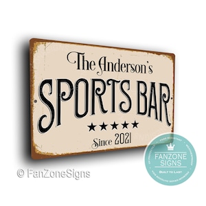 May include: A vintage-style metal sign with a distressed background. The sign reads "The Anderson's Sports Bar Since 2021" with five stars below the text. The sign has a brown border and a white background.