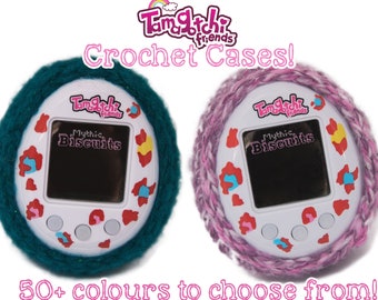 May include: Two Tamagotchi digital pet game consoles in crochet cases. One is teal, the other is pink. The text "Tamagotchi Friends" and "Mythic Biscuits" are visible. The image also shows a variety of crochet case colors.