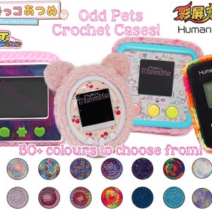 May include: Image of three electronic pet game devices in colorful crochet cases. The cases are pink, light blue, and black, with the text "Mythic Biscuits" on the screens. The image also shows a variety of yarn colors.