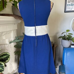 Peut inclure: Une robe bleue sans manches avec une bande blanche autour de la taille. La robe a une fermeture &eacute;clair dans le dos.