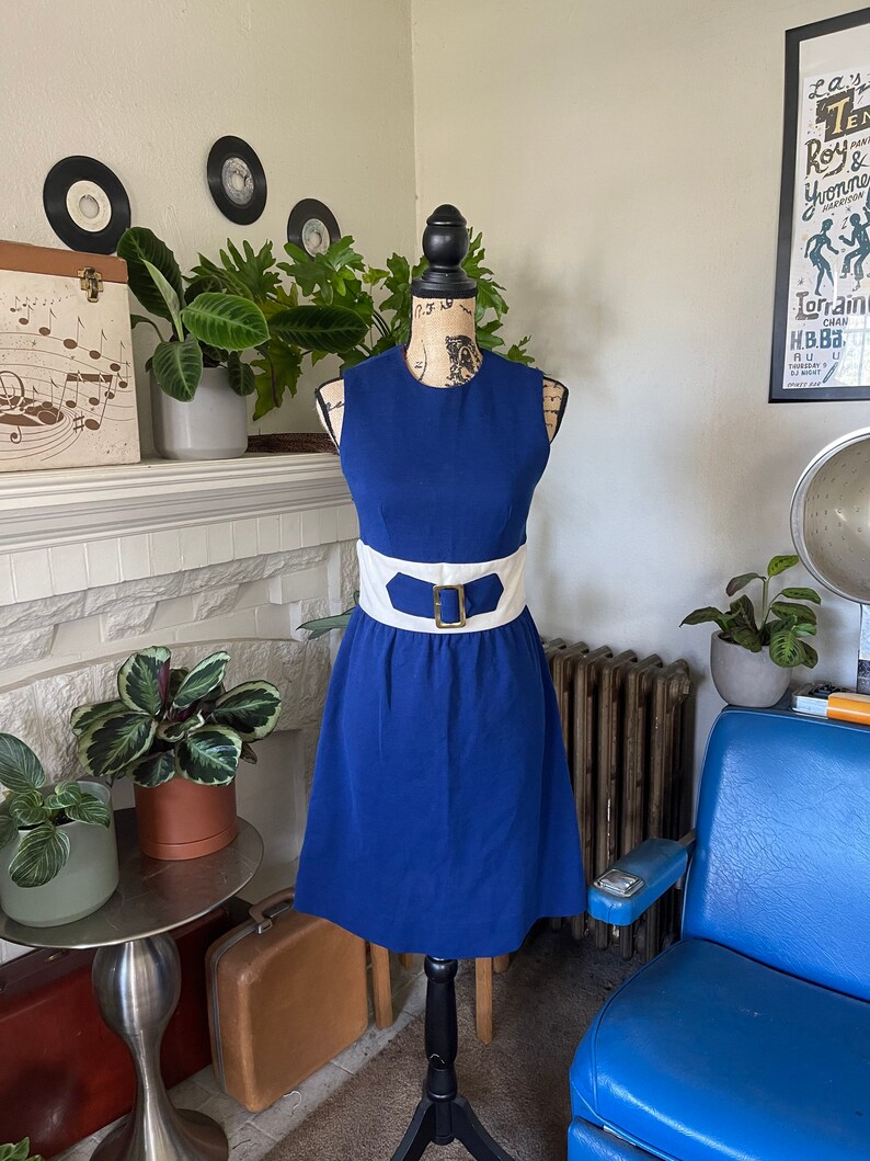 Peut inclure: Une robe sans manches bleu roi avec une ceinture blanche et une boucle dor&eacute;e. La robe a un corsage ajust&eacute; et une jupe &eacute;vas&eacute;e.